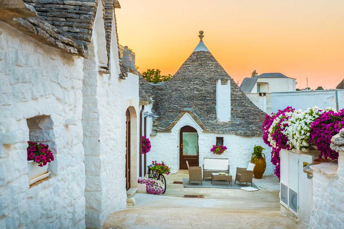Scorcio notturno di trulli durante l’Alberobello Light Festival con installazioni luminose e persone che passeggiano