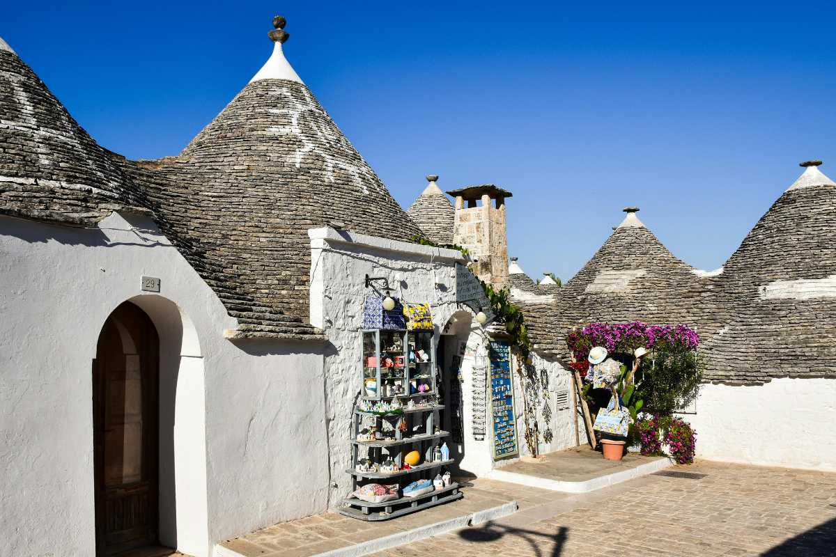 Scorcio del centro storico di Locorotondo con trulli e case bianche, fiori sui balconi, atmosfera primaverile, dettagli architettonici